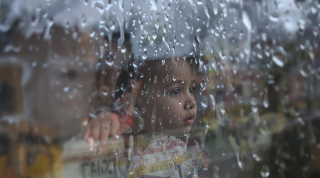 Child looking out rainy window